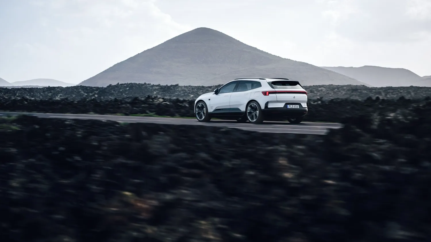 Polestar 4 SUV driving on a road with a mountain behind