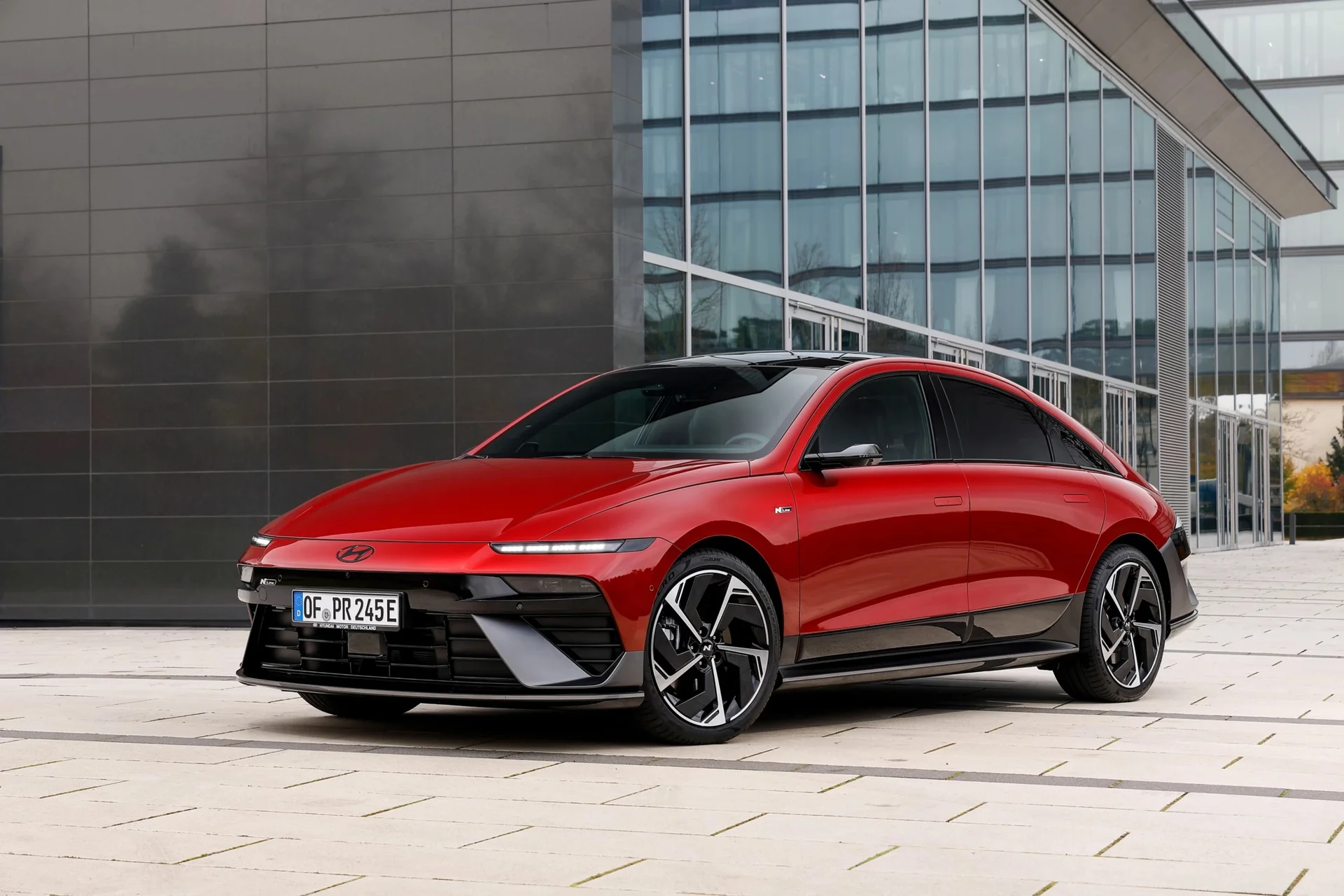 Red Hyundai Ioniq 6 N Line front three-quarter view outside a glass building