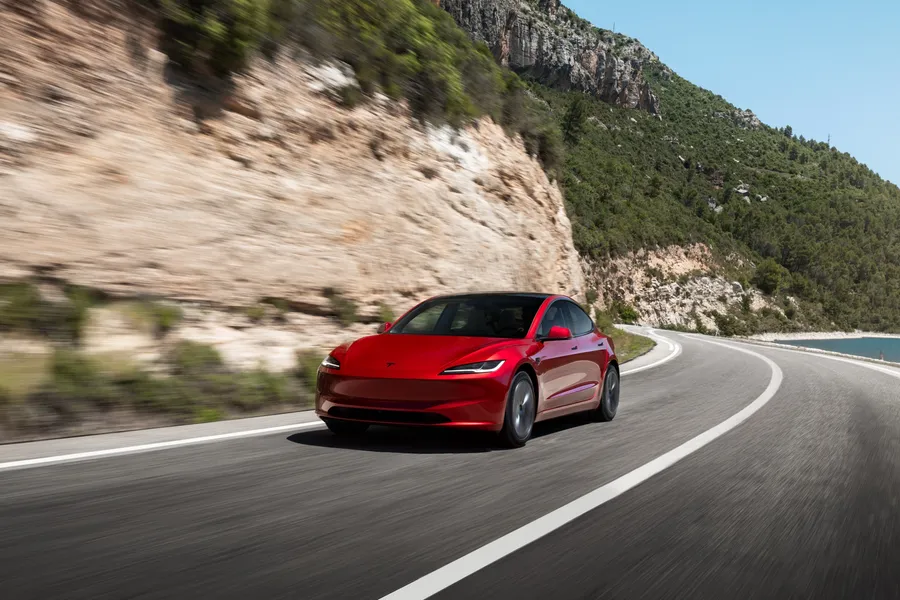 Red Tesla Model 3 Premium driving on a coast road