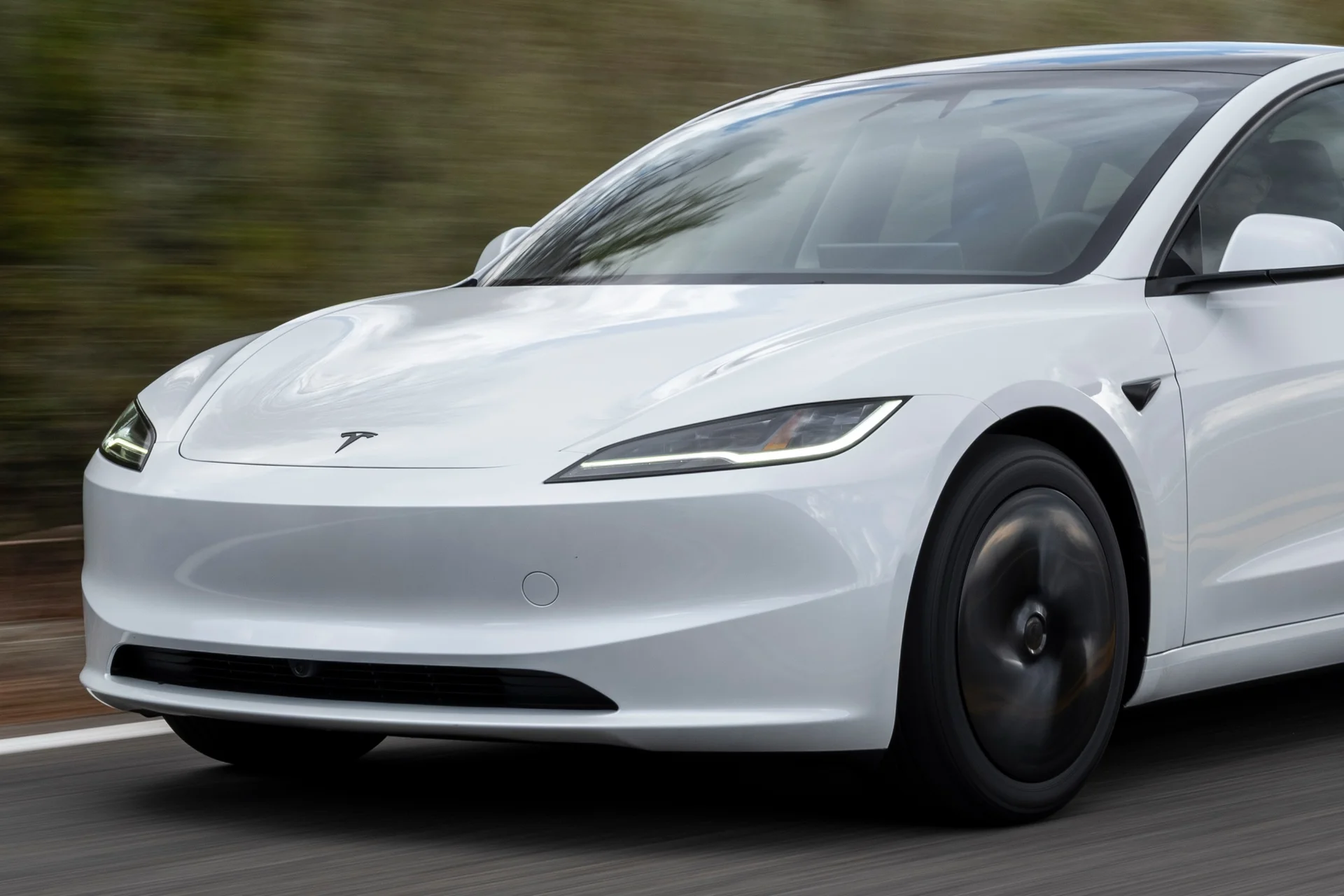 White Tesla Model 3 driving, front three-quarter view